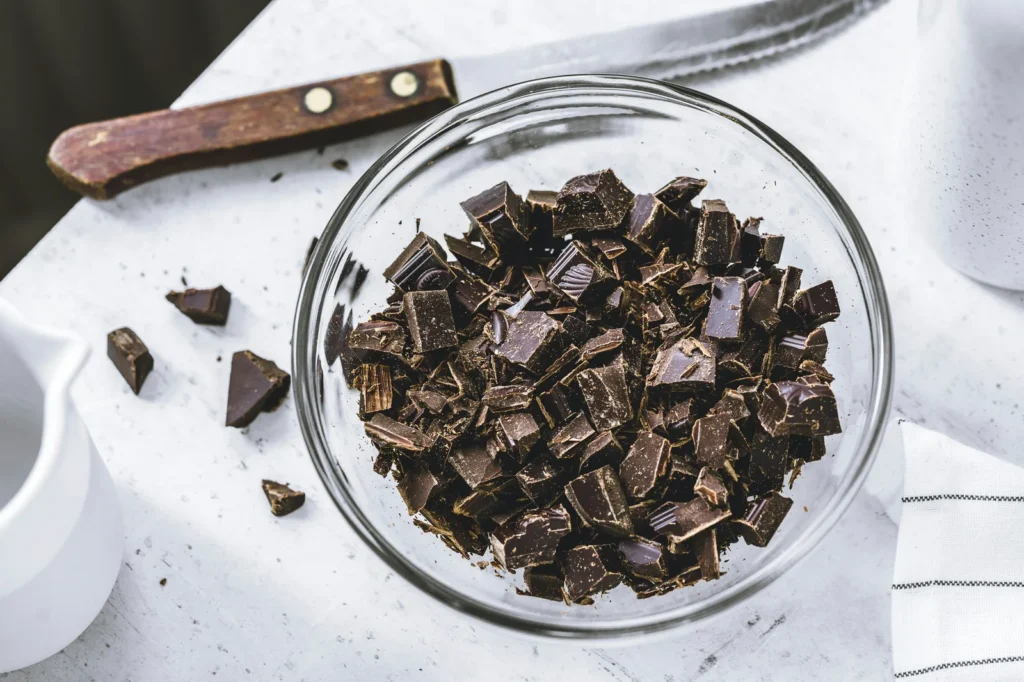 Chocolat noir concassé dans un bol en verre, l'un des aliments qui apportent de l'épicatéchine