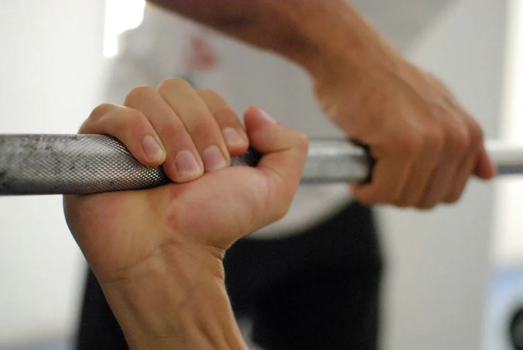 Deux mains qui serrent une barre de musculation moletée, vues de près