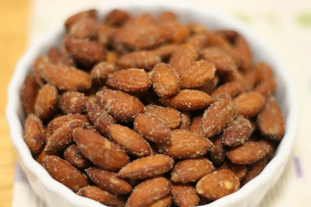 Bol blanc rempli d'amandes grillées posé sur une table